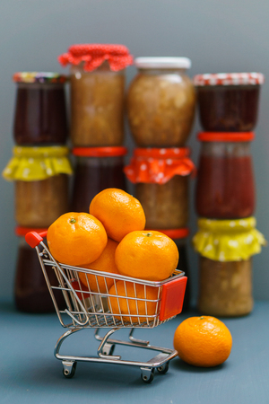 Mandarines in the shopping cart on the background with jam potsの写真素材