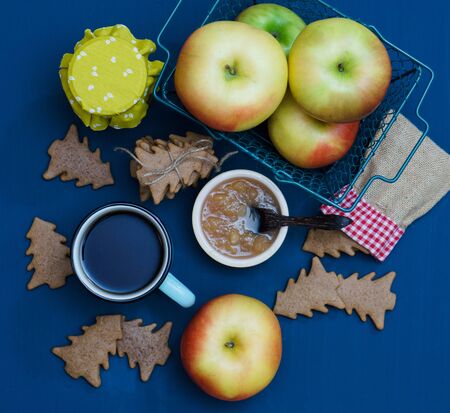 A cup of tea with jam, christmas tree cookies and apples on the dark blue backgroundの写真素材