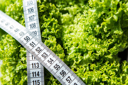 Fitness tape measure on the green salad on white backgroundの写真素材