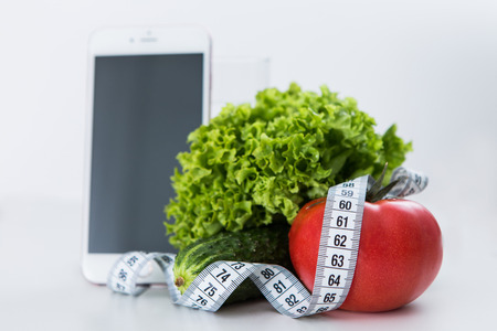 Mobile phone application for dieting and fitness, tape measure with vegetablesの写真素材
