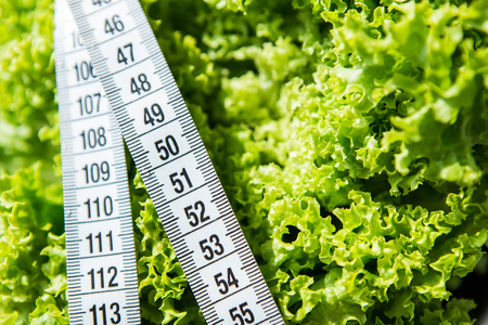 Fitness tape measure on the green salad on white backgroundの写真素材