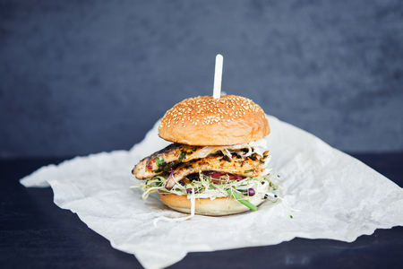 Freshmade streetfood fishburger on the butter-paper on the black backgroundの写真素材