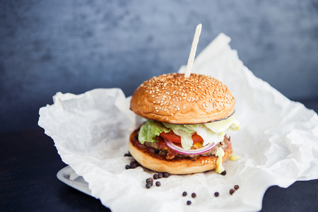 Burger with peper on the butter-paper on the black backgroundの写真素材