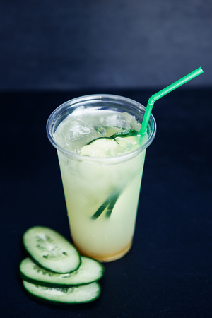 Cucumber lemonade in plastic cup on the black backgroundの写真素材
