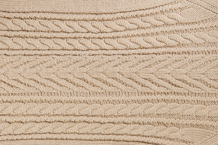 Closeup knitted textile pattern in beige color as background