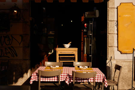 Classical outdoor street cafe in Milan, Italy. Table with old chairs on the street of european city. Romantic and picturesque view with light and shadow, italian style.の写真素材