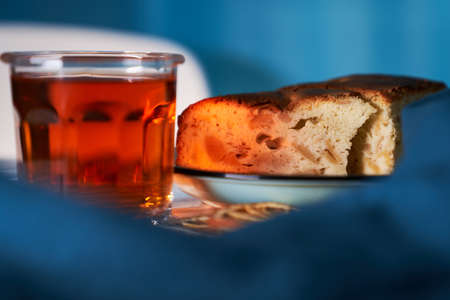 Tea in the glass with apple pie and orange slices on the table with blue backgroundの写真素材