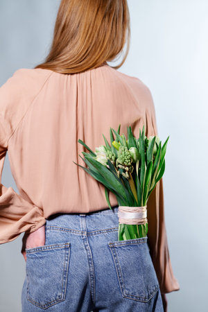Woman with a bouquet of tulip flowers in pocket of her jeans. Art portrait of a woman for the cover of the book or birthday conceptの写真素材