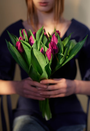 Mother's Day, St. Valentine's day or International Woman's Day concept. Stylish attractive girl in blue blouse and jeans with a tulip flowers bouquet, spring themeの写真素材