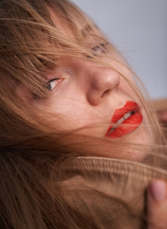 Indoor fashion portrait of glamor lady with perfect make-up, full red lips, long hair and big eyes posing on gray background. Attractive sexy and young girlの写真素材