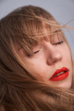 Indoor glamor portrait of attractive lady with perfect make-up, full red lips, long hair and big eyes posing on gray background. Attractive sexy and young girlの写真素材