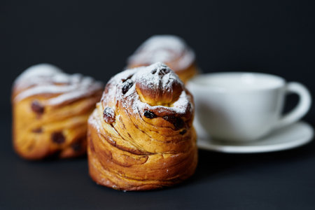 Tasty fresh baked cruffins with white cup of coffee or tee on dark background. Traditional Easter pie or bakery concept. High quality photoの写真素材