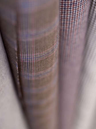 Online sale or tailoring objects concept. Closeup bunch of warm wooled tweed textile rolls in different colors and patterns. Fabrics retail store, atelier, drapery or textile shopの写真素材