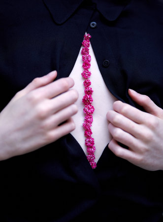 Woman opens black shirt and there is a line of pink daisy flowers on a body. Aesthetic flowers usage concept. Tiny cute daisy flowers. High quality vertical photoの写真素材