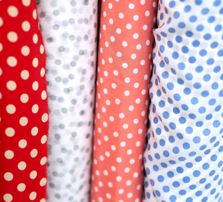 Close-up multicolored polka dotted fabrics linen cloth in rolls. Rows of minimalist red, blue and white colors. Sewing or tailoring concept. High quality vertical photoの写真素材