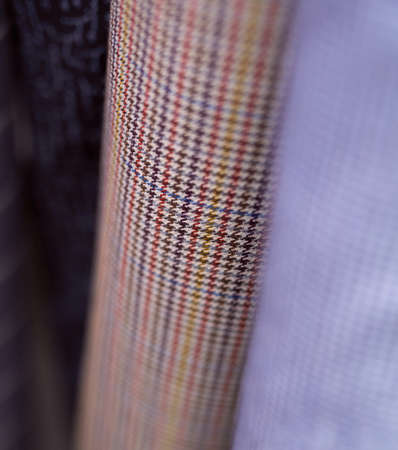 Closeup bunch of warm linen tweed textile rolls in different colors and patterns. Fabrics retail...