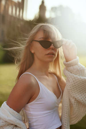 Cheerful happy teen at summer with sun-flares. Fashion aesthetic portrait of stylish happy girl outdoor. Smiling caucasian blonde teenage hipster girl wearing black sunglasses. High quality photoの写真素材