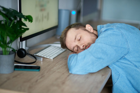 Software developer of web designer: caucasian bearded tired IT guy sleeping and awaking at working place in office. Man sleeping at desk, tired of stressful job burnout at work, lack energyの写真素材