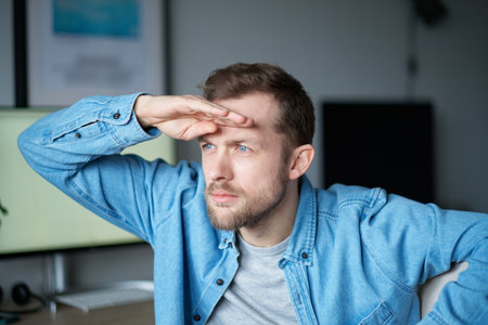 Cute bearded portrait of caucasian male freelance software engineer sitting at working place in office looking forward for new opportunities with computer on background. High quality imageの写真素材