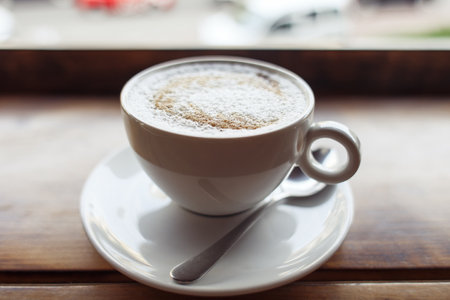 Cappuccino coffee in white cup on the table with the spoon, coffee break concept High quality photoの写真素材