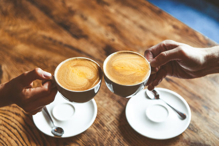 two cups of cappuccino coffee in friends hands, coffee break concept. High quality photoの写真素材