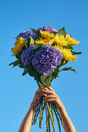 hands holding a bouquet of blue hydrangea on the background of blue sky , spring summer concept. High quality photoの写真素材