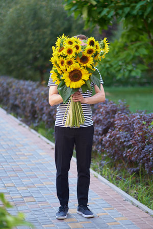 bouquet of yellow sunflowers in hands of an unrecognisable man outdoor . Patriotic gift with love, gratitude. Mothers Day. Support for Ukraine. Independence Day. High quality photoの写真素材
