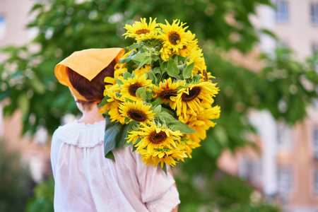 bouquet of yellow sunflowers in hands of an unrecognisable woman outdoor . Patriotic gift with love, gratitude. Mothers Day. Support for Ukraine. Independence Day. High quality photoの写真素材