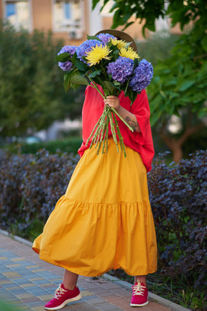 woman in red shirt holding a bouquet of blue hydrangea on the background of green garden , spring summer concept. High quality photoの写真素材