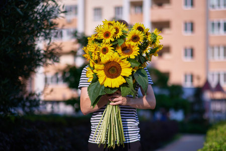 bouquet of yellow sunflowers in hands of an unrecognisable man outdoor . Patriotic gift with love, gratitude. Mothers Day. Support for Ukraine. Independence Day. High quality photoの写真素材