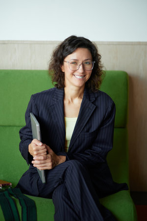 Portrait of a business woman with glasses smiling and happy with laptop. Dark blue jacket, confident woman looking in the camera High quality photoの写真素材