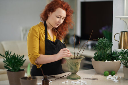 Attractive caucasian woman gardener taking care of plants in flower shop. Indoor botanical, eco or greenhouse concept theme. High quality imageの写真素材