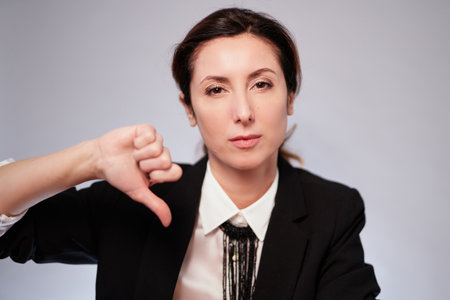 Serious business lady in black jacket posing with negative gesture on isolated background. Cheerful manager woman in dark suit looking at camera. High quality photoの写真素材