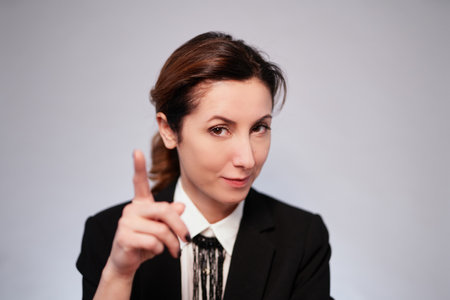 Emotional brunette caucasian business lady in black jacket posing on isolated background pointing at camera with finger. Happy cheerful manager woman in dark suit. High quality photoの写真素材