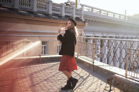 Fashion portrait of stylish elegant lady. Cute blonde young caucasian girl in beret, black jacket and red polka dot dress posing outside in the city looking at camera. High quality imageの写真素材