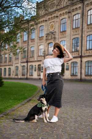 Pretty young woman and dog sitting on the old city scape smiling at camera. Smiling and hugging the dog. Old city scape. High quality photoの写真素材
