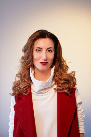 Businesswoman, female boss or fashion portrait concept. Stylish smiling brunette with wavy hair and brown eyes in perfect maroon suit. High quality vertical photoの写真素材