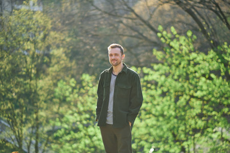 Young man smiling confident standing at park in the sunlight looking at the camera. High quality photoの写真素材