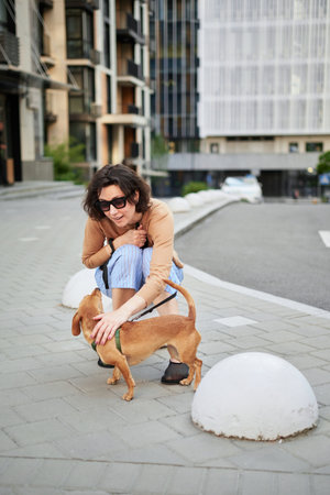 Young female adult in the city with a dog sitting and hugging, smiling. Petting the dog, feeding, having fun High quality photoの写真素材