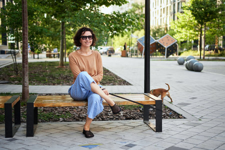 Young female adult in the city with a dog sitting and hugging, smiling. Petting the dog, feeding, having fun High quality photoの写真素材