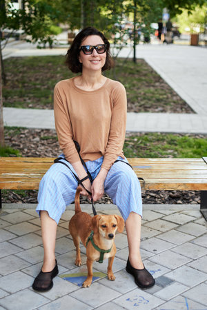 Young female adult in the city with a dog sitting and hugging, smiling. Petting the dog, feeding, having fun High quality photoの写真素材