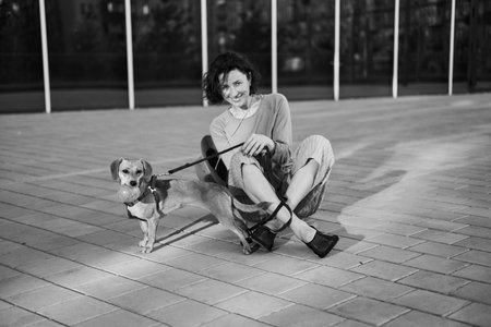 Young female adult in the city with a dog sitting and hugging, smiling. Petting the dog, feeding, having fun High quality photoの写真素材