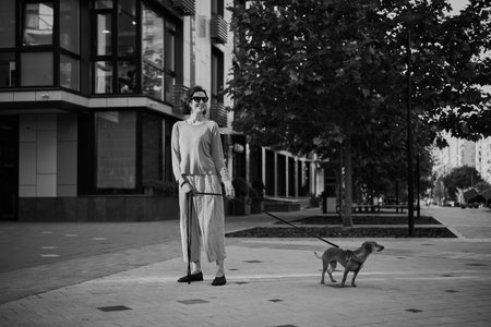 Young pretty female adult with small ginger dog in the bi city walking having fun. City view High quality photoの写真素材
