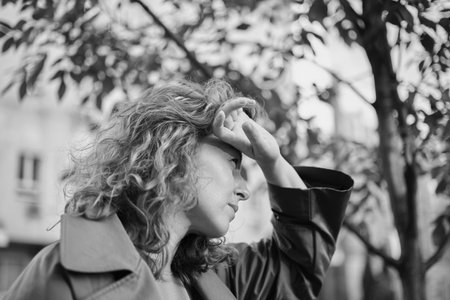 Cropped closeup portrait of a caucasian mature beautiful woman wife looking at the sun in park outdoors streets hiding from the sunset sun in sad serious mood. High quality photoの写真素材