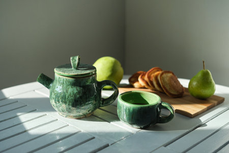 Delicious breakfast, snack pancakes, green tea, fresh pear, green teapot, tea on a gray background, morning sun . High quality photoの写真素材