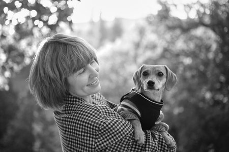 Owner walking with dog together in park outdoors, summer vacation, Adorable domestic pet concept, Friendship between human and their pet. Dachshund in sweater High quality photoの写真素材
