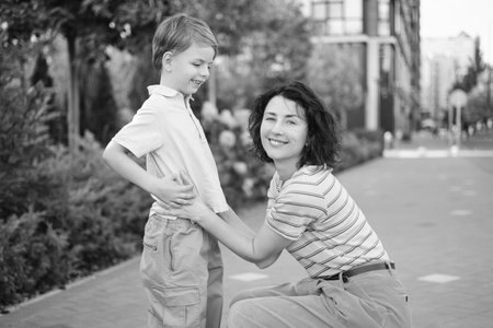 young mother and son smiling looking at the camera in modern residential complex. Having fun together, happy parenting, new home concept. Bright summer day in the urban background. High quality photoの写真素材