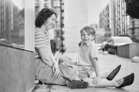 Adorable mother and son smiling happy having fun at city background. Motherhood concept, hugging. Boy 8 years old with mother in bright clothes enjoying summer day. High quality photoの写真素材