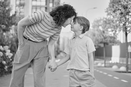Adorable mother and son smiling happy having fun at city background. Motherhood concept, hugging. Boy 8 years old with mother in bright clothes enjoying summer day. High quality photoの写真素材
