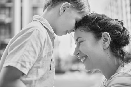 Adorable mother and son smiling happy having fun at city background. Motherhood concept, hugging. Boy 8 years old with mother in bright clothes enjoying summer day. High quality photoの写真素材
